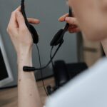 Close-up of a person holding a headset in a call center, indicating service and communication.